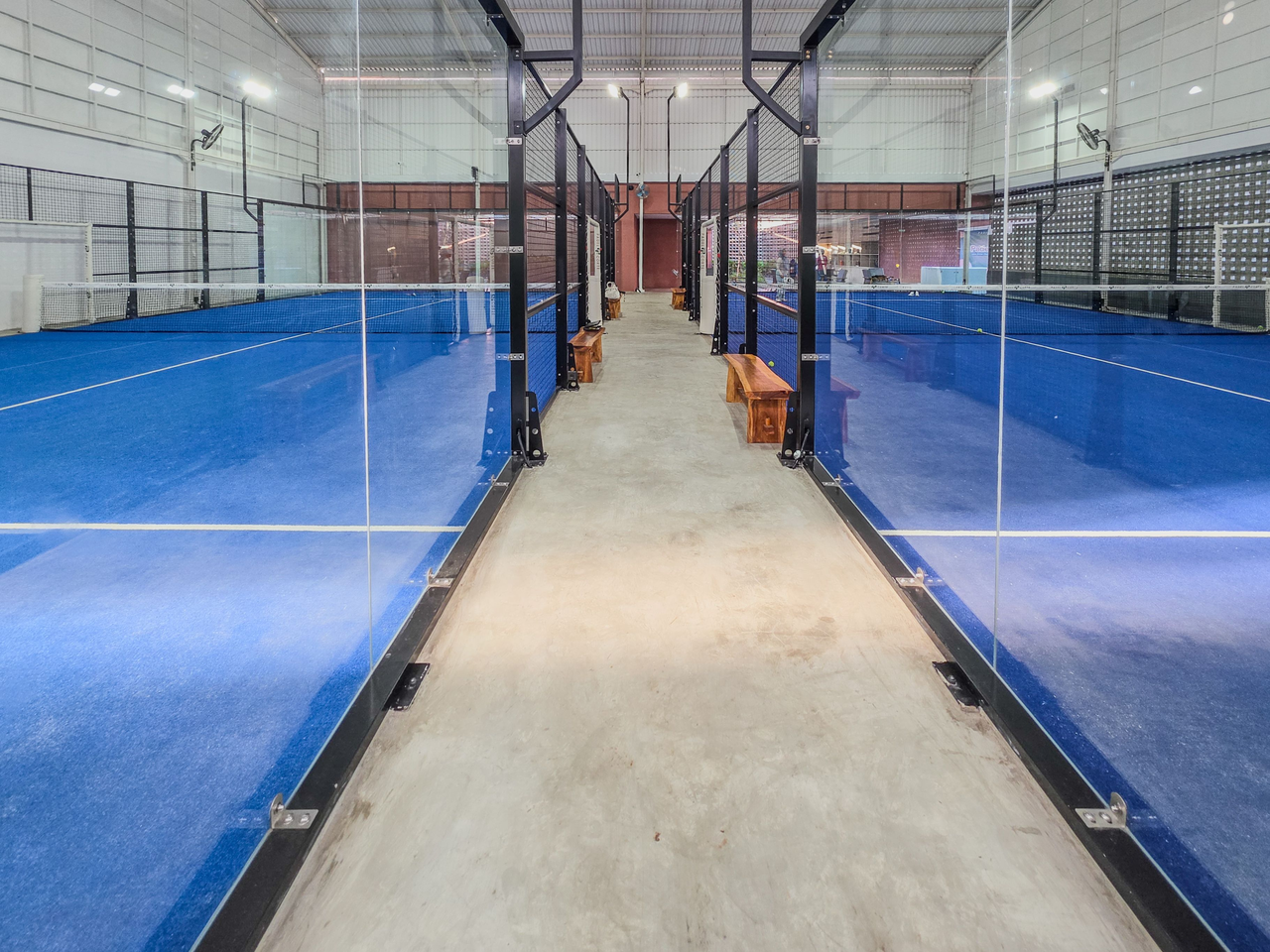 Glass walls surrounding indoor blue padel courts